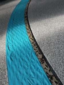 A close-up of a curved blue strip and a worn metal strip on a speckled gray surface. A close-up of a curved blue strip and a worn metal strip on a speckled gray surface.