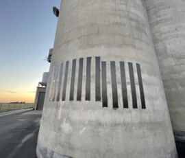 Concrete industrial silo featuring a series of vertical black rectangular panels.