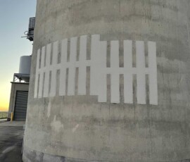 Large concrete silo featuring a painted white tally mark pattern.